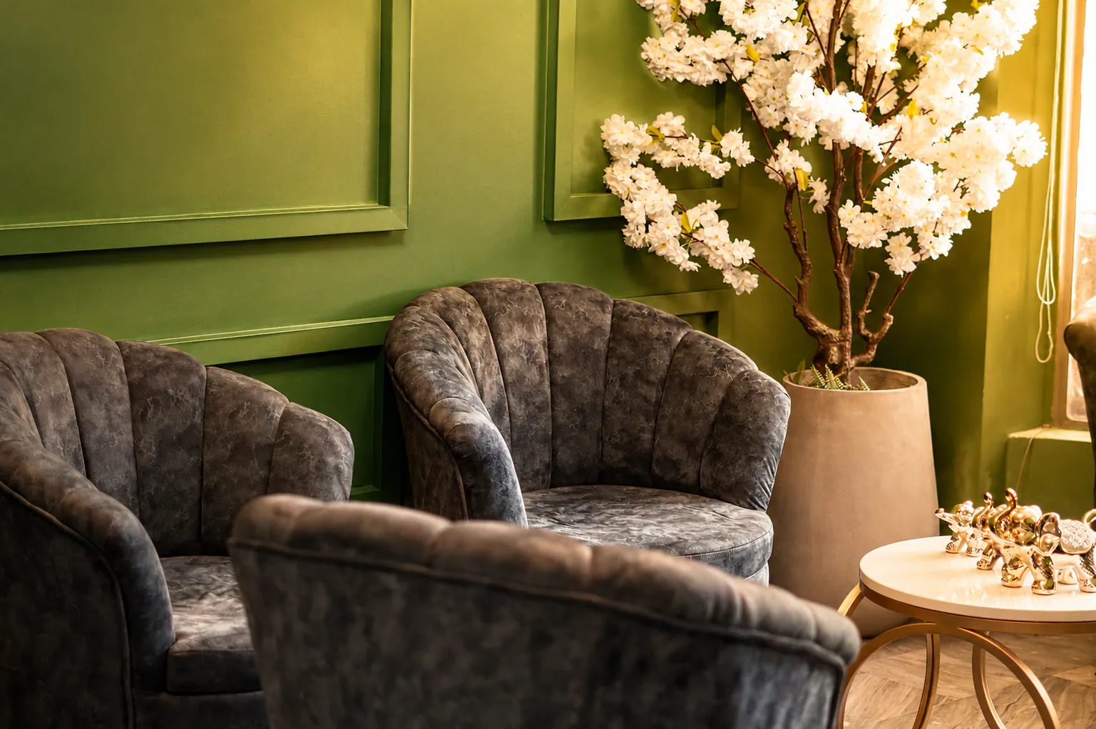 Sala de espera verde con mobiliario y flores en Makai Spa